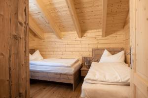 a room with two beds in a wooden cabin at Feriendorf Koralpe Wellness Edelweiß in Frantschach