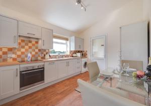 a kitchen with white cabinets and a glass table at The Paddocks in Horstead