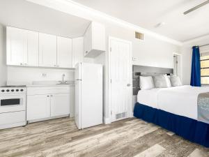 a white bedroom with a bed and a kitchen at Neptune Oceanfront Rentals in Hollywood
