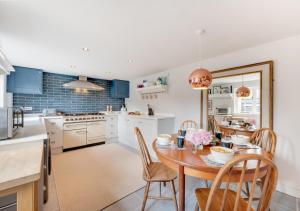 a kitchen with a table and chairs and a kitchen with blue cabinets at The Hayloft in Dilham