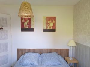 a bedroom with a bed and three pictures on the wall at Chalet le logis des autre in Vireux-Wallerand