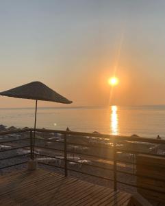 a sunset on the beach with an umbrella at BELCAN Hotel in Beldibi