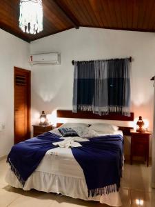 a bedroom with a bed with a blue blanket and a window at Porto do Sol - Chalé 21 in Pipa