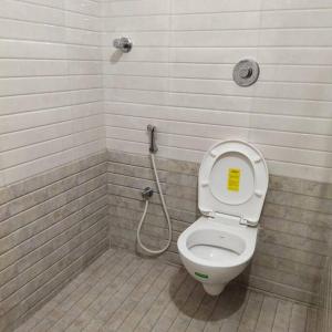 a bathroom with a toilet with a yellow sign on the lid at Sapphire Luxury Apartment in Puducherry