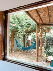 ein Fenster mit Blick auf eine Hängematte im Garten in der Unterkunft Bangalô de Charme na Praia do Patacho - Rota Ecológica dos Milagres in Pôrto de Pedras