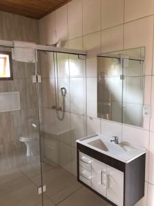 a bathroom with a sink and a glass shower at Pousada Caminhos da Serra in Bom Retiro