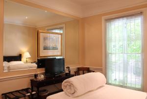 1 dormitorio con 1 cama, TV y ventana en Tintagel Guesthouse, en Ciudad del Cabo