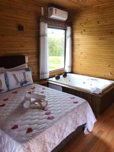 um quarto com uma cama e uma banheira com uma janela em Pousada Caminhos da Serra em Bom Retiro
