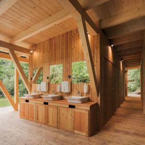 ein Badezimmer mit vier Waschbecken in einem Holzgebäude in der Unterkunft Camping Naturplac Na Skali in Ljubno