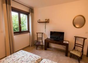 Schlafzimmer mit einem TV, einem Schreibtisch und einem Spiegel in der Unterkunft chambre d'hôtes de charme, un temps en forêt in Westhouse