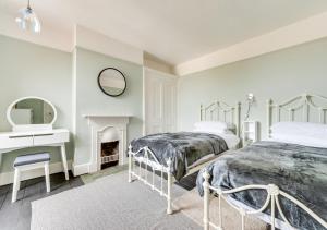 a white bedroom with two beds and a mirror at Felixstowe Beach House in Felixstowe