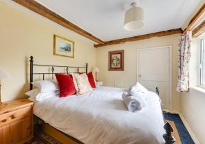 a bedroom with a large white bed with red pillows at Appletree Cottage in Westleton