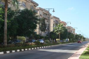 uma rua com carros estacionados ao lado de um edifício em Maamoura Beach 2 em Alexandria