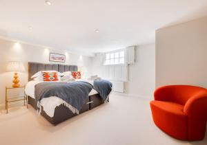 a bedroom with a bed and a orange chair at Barley Rise in Southwold