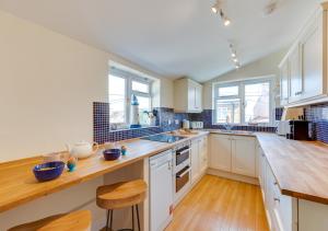 a kitchen with white cabinets and wooden floors and windows at Brightseas in Southwold