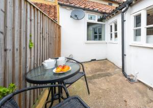 a table with a bowl of fruit on a patio at London Cottage in Halesworth
