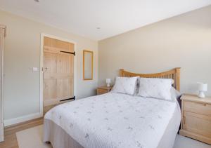 NeedhamにあるThe Cart Lodgeの白いベッドと木製のドアが備わるベッドルーム1室が備わります。