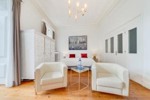a white bedroom with a bed and two white chairs at Chiado 44 in Lisbon