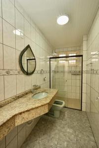 a bathroom with a sink and a toilet and a mirror at Apartamento Vera in Florianópolis