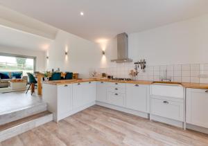 uma cozinha com armários brancos e pisos em madeira em Bramble Cottage em Leiston