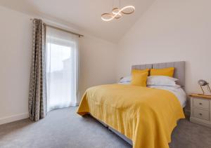 um quarto com uma cama com um cobertor amarelo e uma janela em Bramble Cottage em Leiston