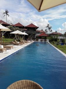 a large swimming pool with chairs and umbrellas at Gubug Balian Beach Bungalow in Selemadeg