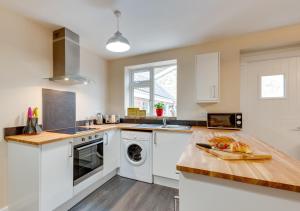 a kitchen with white cabinets and a washer and dryer at Ardley Cottage Squirrel in Waldingfield