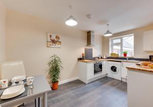 a kitchen with white cabinets and a table with a plant at Ardley Cottage Squirrel in Waldingfield