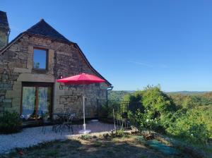 un ombrello rosso seduto di fronte a un edificio di Gîte au calme avec superbe vue : La Talonie a Mouret