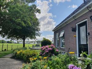 Vakantieboerderij Huize Nuis في Noordbeemster: حديقة خارج منزل من الطوب مع الزهور
