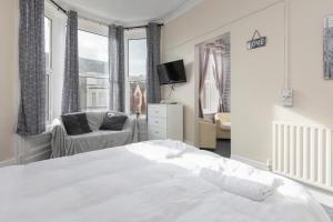 a white bedroom with a bed and a chair at The B & B Blackpool in Blackpool