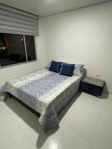 een slaapkamer met een bed met blauwe kussens en een raam bij Hermoso apartamento en Barbosa Santander in Barbosa