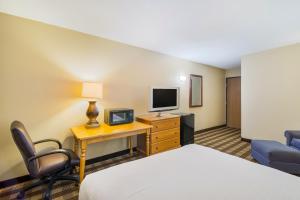 Habitación de hotel con cama y escritorio con TV. en Americas Best Value Inn Fargo, en Fargo