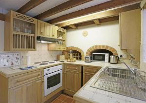 uma cozinha com armários de madeira e um forno de fogão branco em Rose Cottage em Bealings