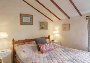 a bedroom with a bed and two tables and two lamps at Rose Cottage in Bealings