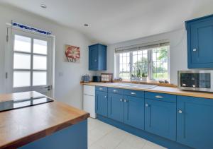 a blue kitchen with white walls and blue cabinets at Mallards in Whepstead