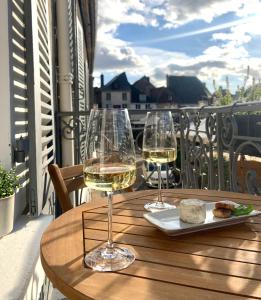 dois copos de vinho sentados numa mesa na varanda em La Place B&B em Sancerre