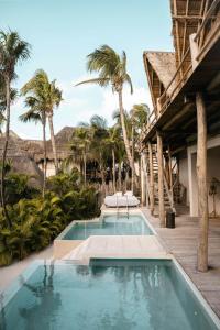 a beach with a pool and palm trees at La Valise Tulum in Tulum