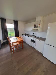 a kitchen with white cabinets and a table and a refrigerator at Vollvaagen Apartments Smøla, boat included in Smøla