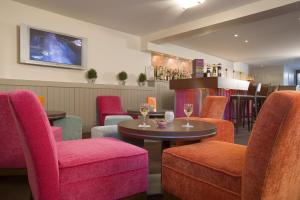 a bar with chairs and a table and wine glasses at Mercure Deauville Centre in Deauville