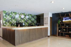 un vestíbulo con un mostrador de recepción con una pared de flores en Hotel Portobelo, en Guadalajara