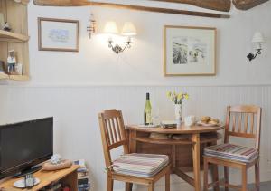 a dining room with a table and chairs and a television at Pebbles Cottage in Southwold