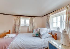 um quarto com uma cama e duas janelas em Corner Cottage em Wangford