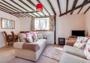 uma sala de estar com dois sofás e uma televisão em Corner Cottage em Wangford