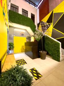 a yellow and black building with a green hedge at ROOMIES HOSTEL Parque México in Mexico City