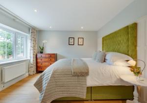 a bedroom with a large bed with a green headboard at Riverside Lodge in Beccles