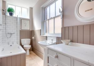 La salle de bains est pourvue d'un lavabo, de toilettes et d'un miroir. dans l'établissement Rest Cottage, à Southwold