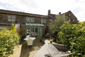 um jardim com mesa e cadeiras em frente a uma casa em BIRDS EDGE COTTAGE - Luxury 2 Bedroom Cottage with Amazing Views, Near Holmfirth in Yorkshire em Denby Dale