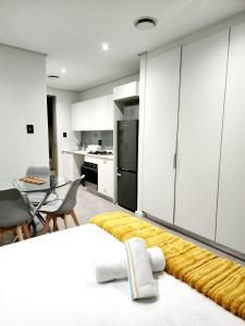 a bedroom with white cabinets and a kitchen with a table at Sugar Shores - Studio Apartment in Sibaya