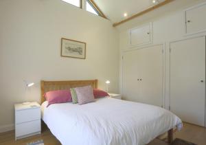 a bedroom with a bed with white sheets and pink pillows at Meadow Cabin in Henstead